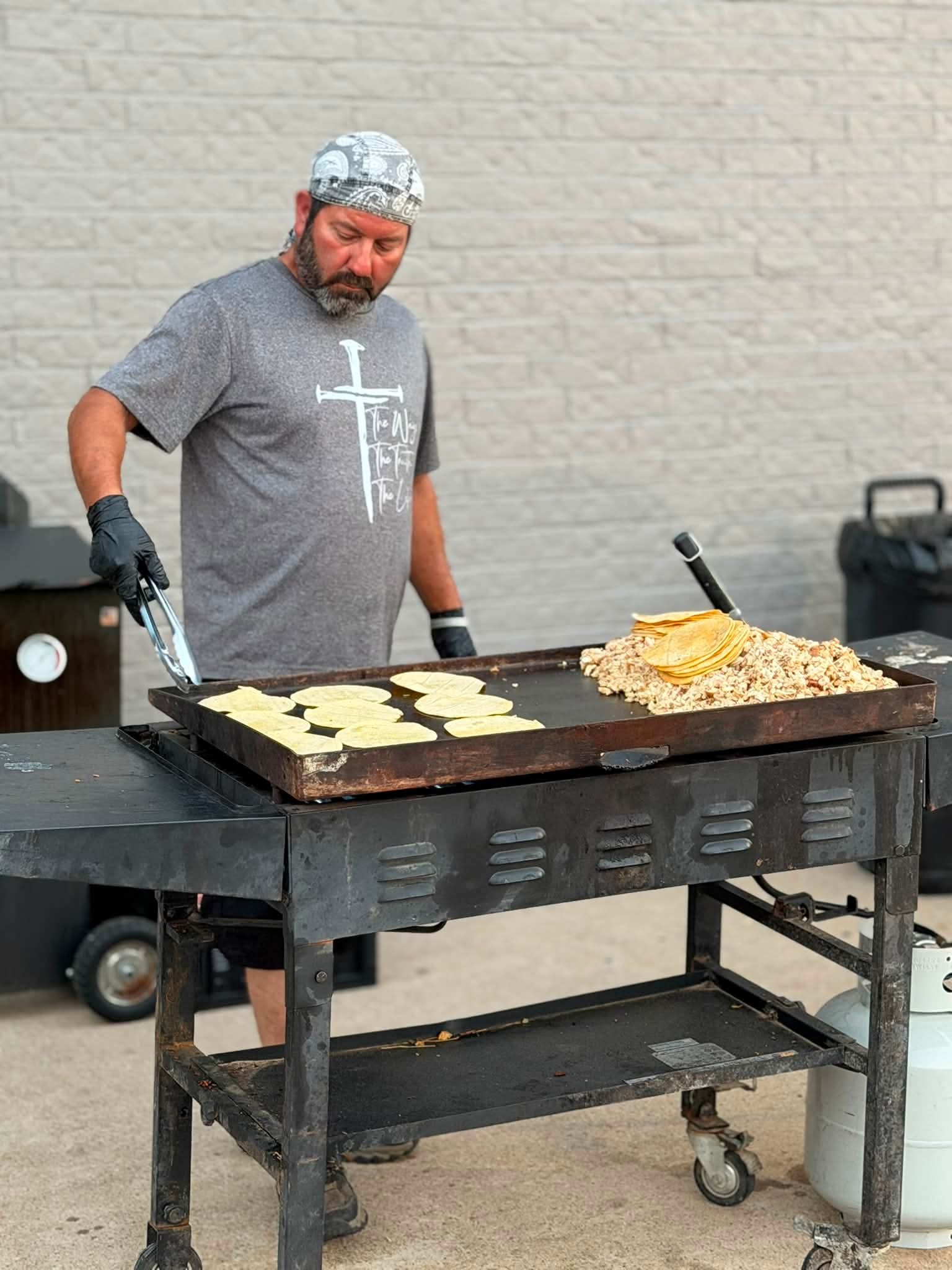 A volunteer preparing tortillas and food on a griddle.