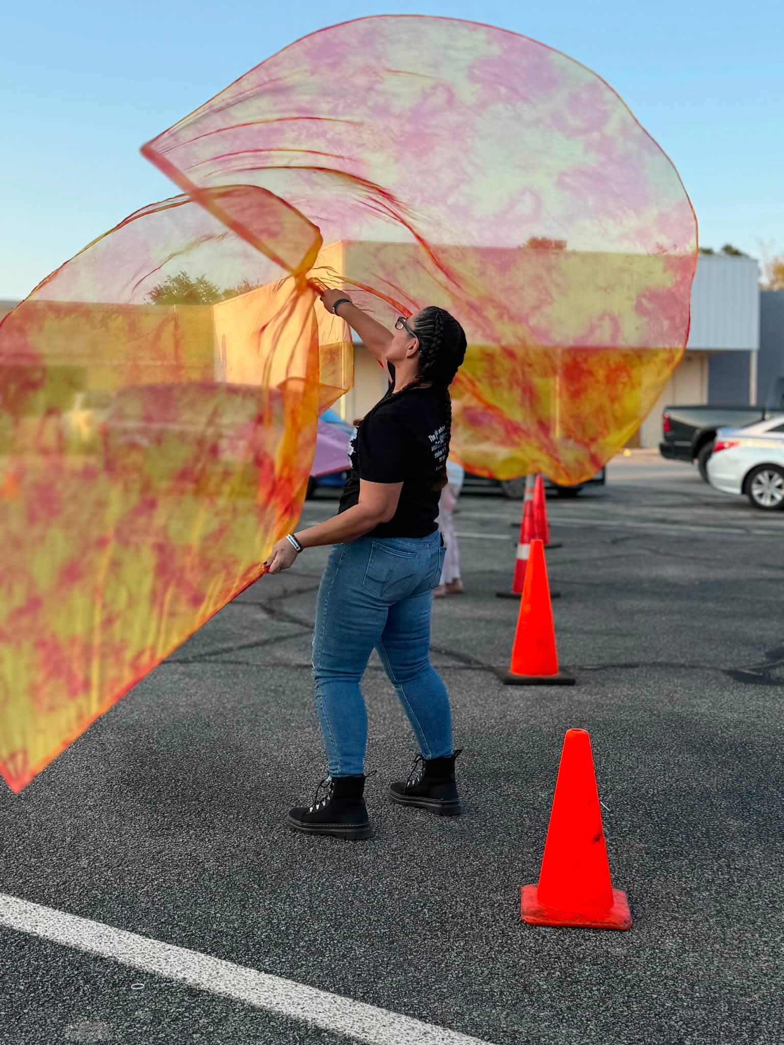 A worshipper moving colorful flags at an outdoor gathering.