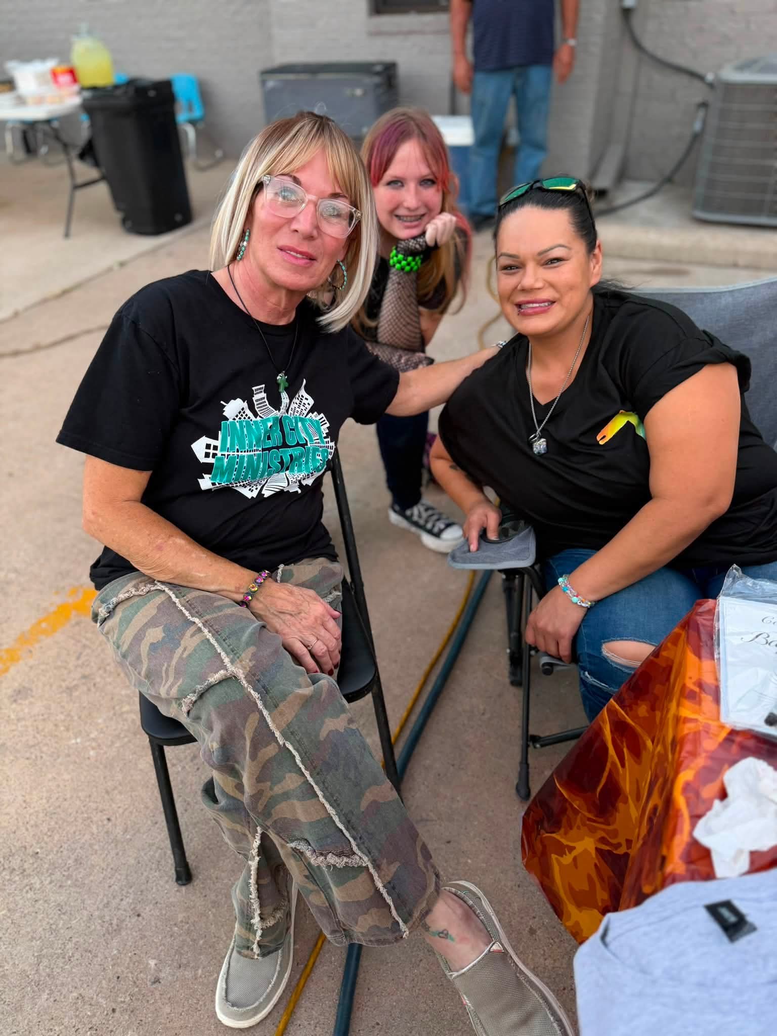 Three community members smiling together at a ministry gathering.